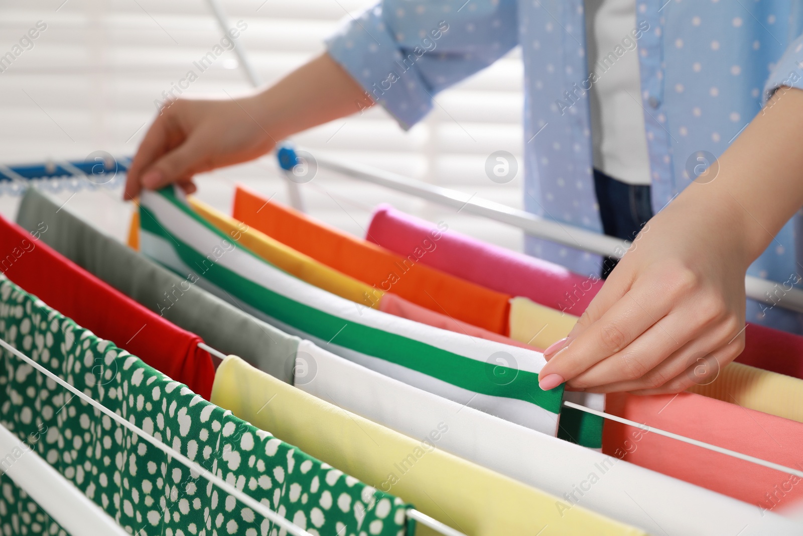 Photo of Woman hanging different apparel on clothes airer, closeup