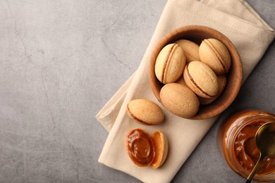 Delicious nut shaped cookies with boiled condensed milk on gray textured table, flat lay. Space for text