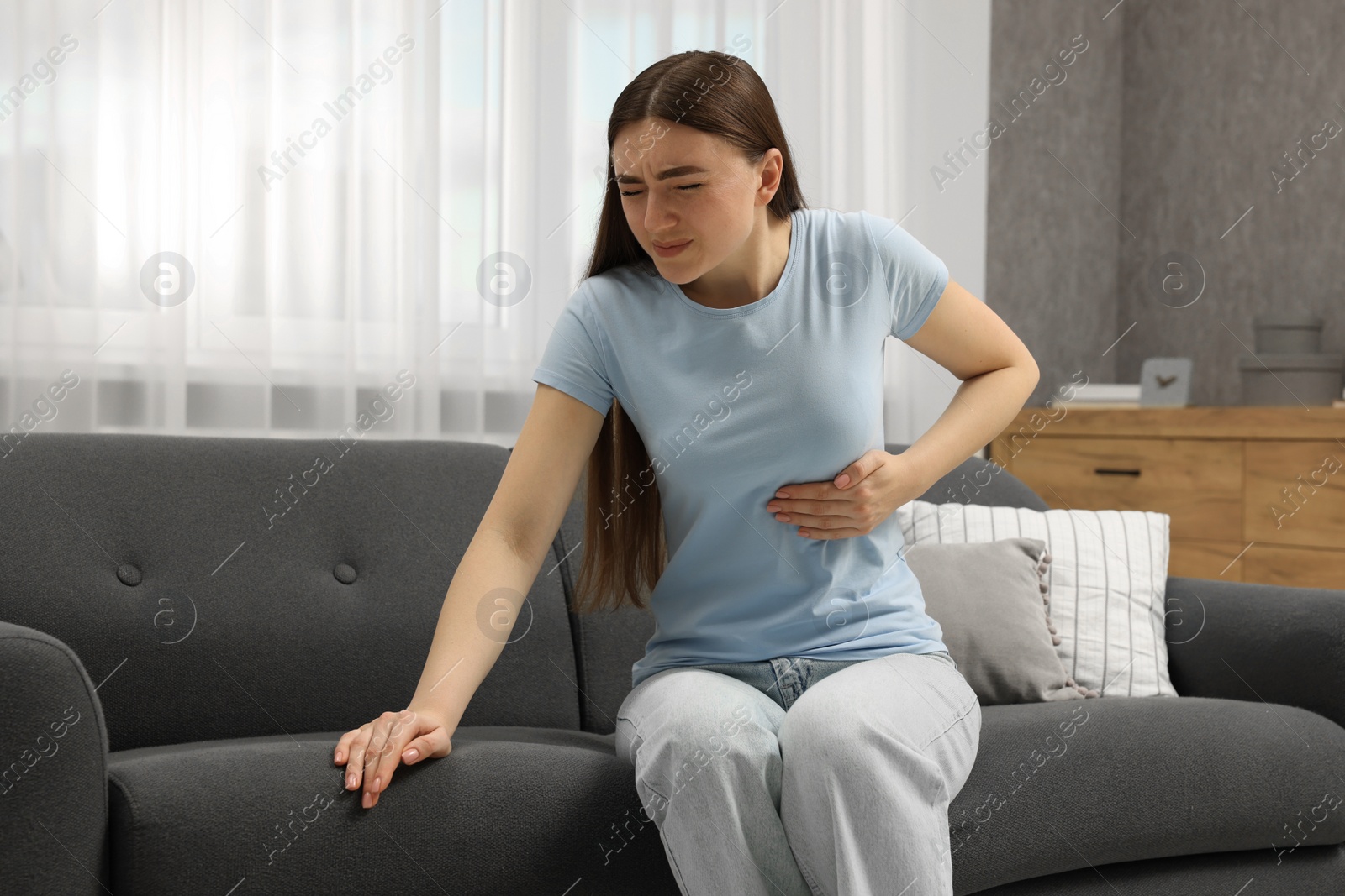 Photo of Woman having heart attack on sofa at home