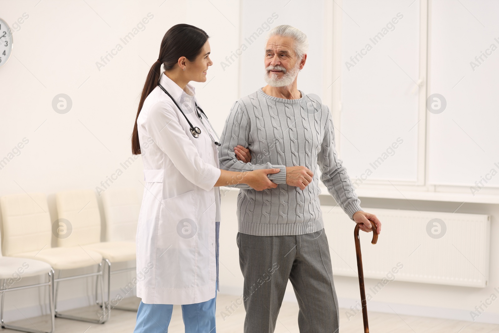 Photo of Smiling nurse supporting elderly patient in hospital