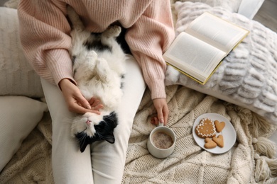 Photo of Woman stroking adorable cat on bed, above view