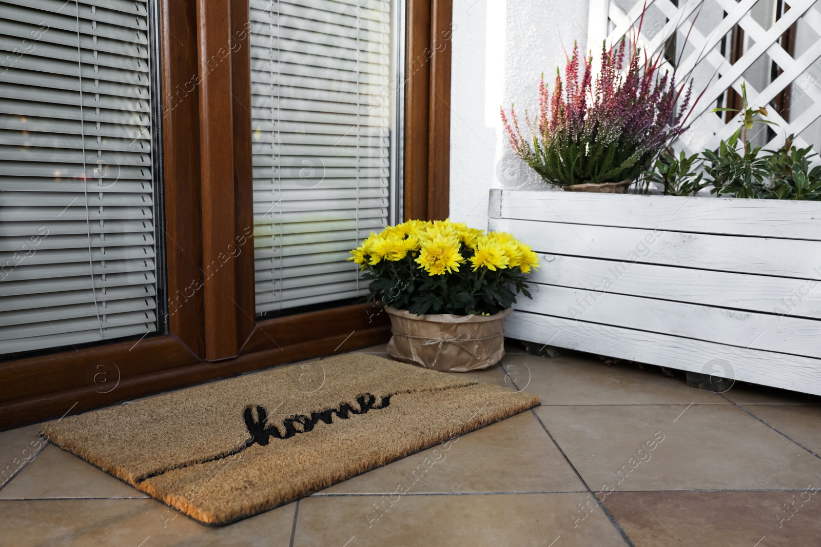 Photo of Doormat with word Home and flowers near entrance outdoors