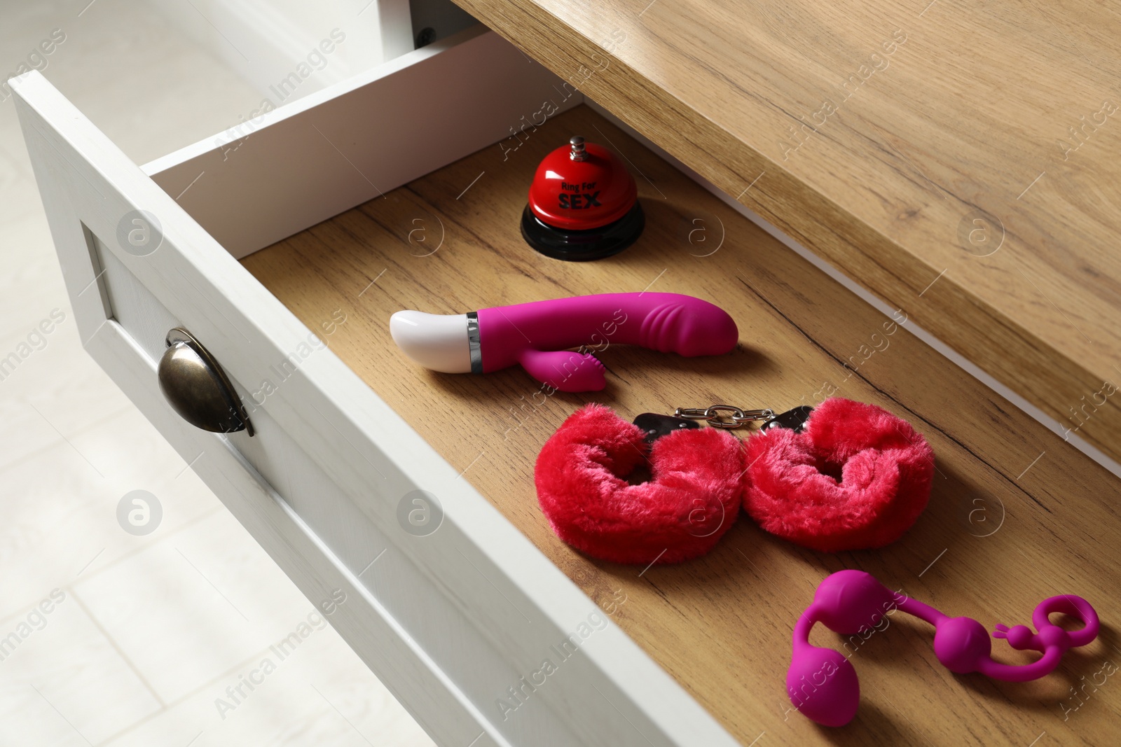 Photo of Different modern sex toys in open wooden drawer