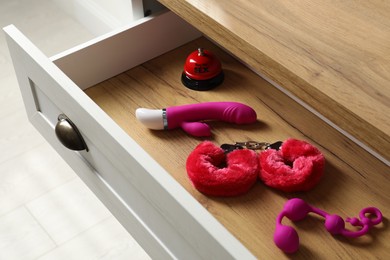 Photo of Different modern sex toys in open wooden drawer
