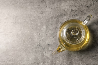 Photo of Glass teapot with oolong on grey background, top view. Space for text