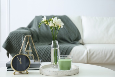 Photo of Vase with beautiful freesia flowers, candle and clock on table indoors, space for text. Interior elements