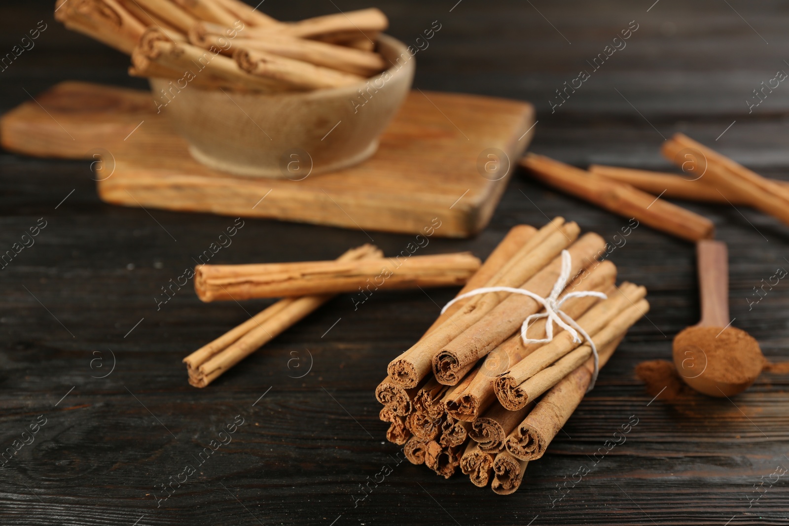 Photo of Aromatic cinnamon sticks on black wooden table, space for text