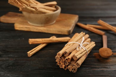 Photo of Aromatic cinnamon sticks on black wooden table, space for text