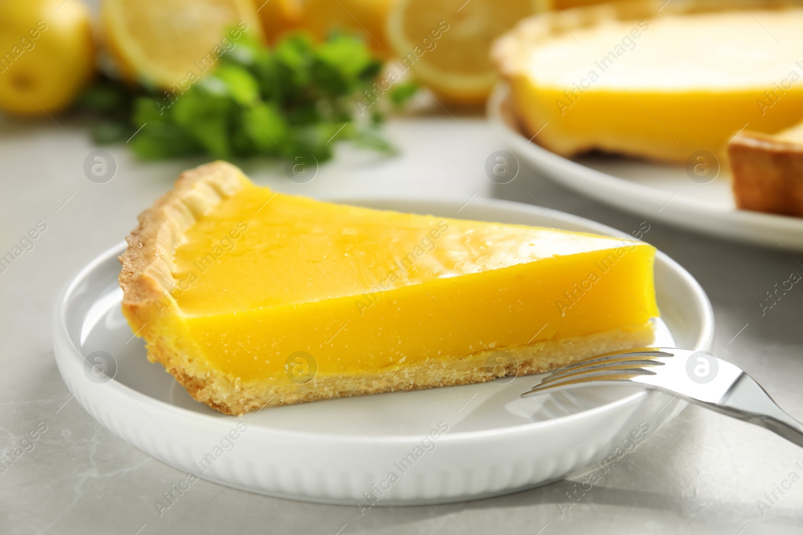 Photo of Slice of delicious homemade lemon pie on light grey table