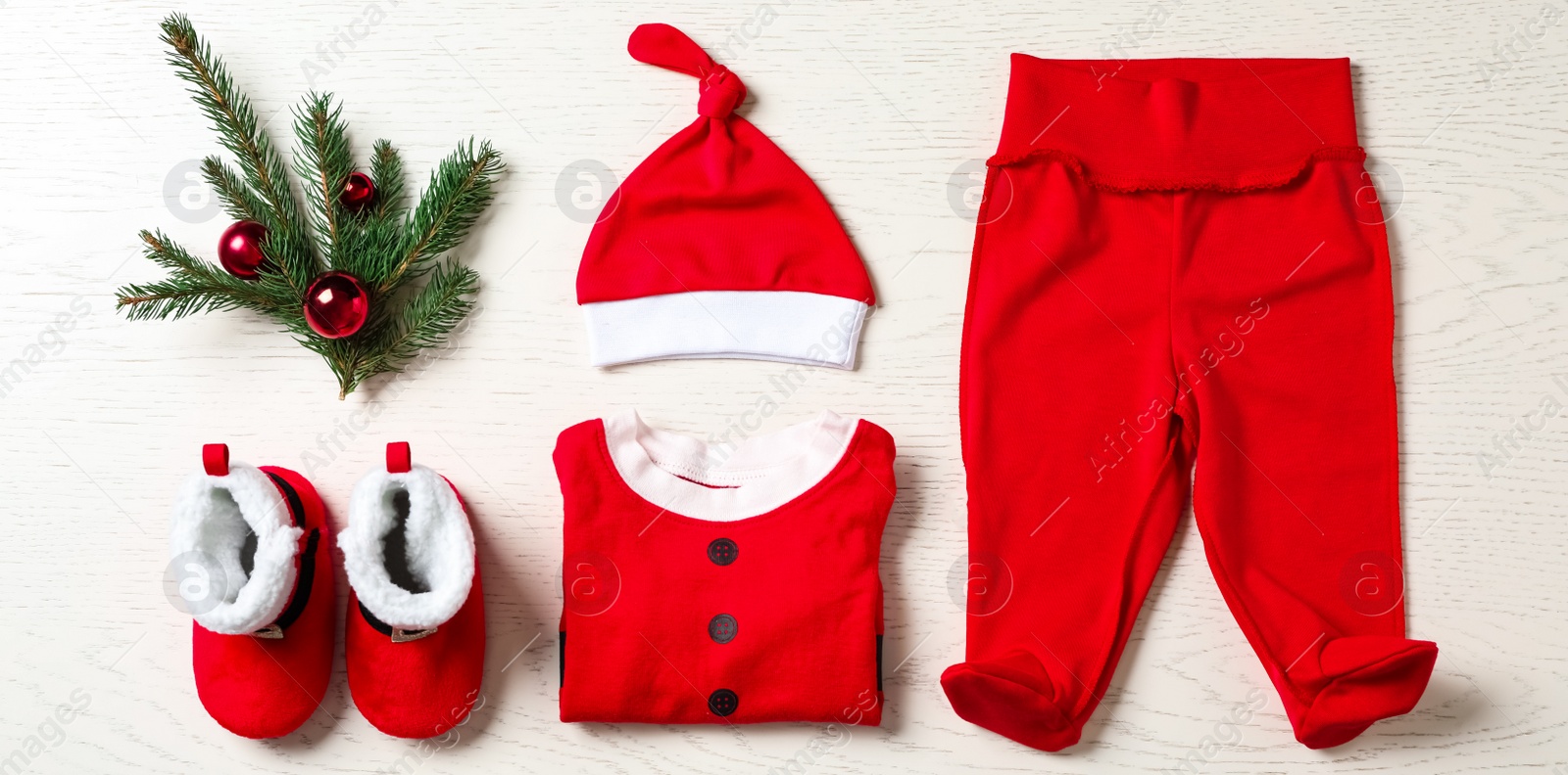 Photo of Flat lay composition with cute Christmas baby clothes on white wooden background