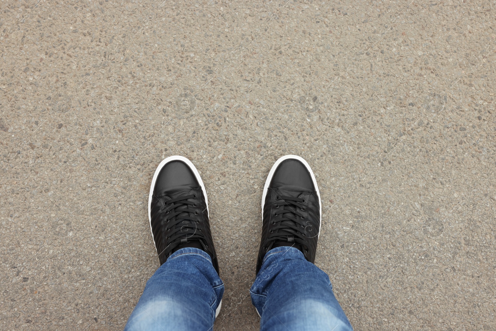 Photo of Man in stylish sneakers standing on asphalt, top view