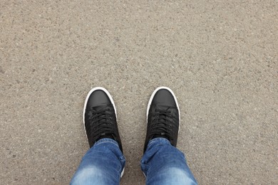 Photo of Man in stylish sneakers standing on asphalt, top view