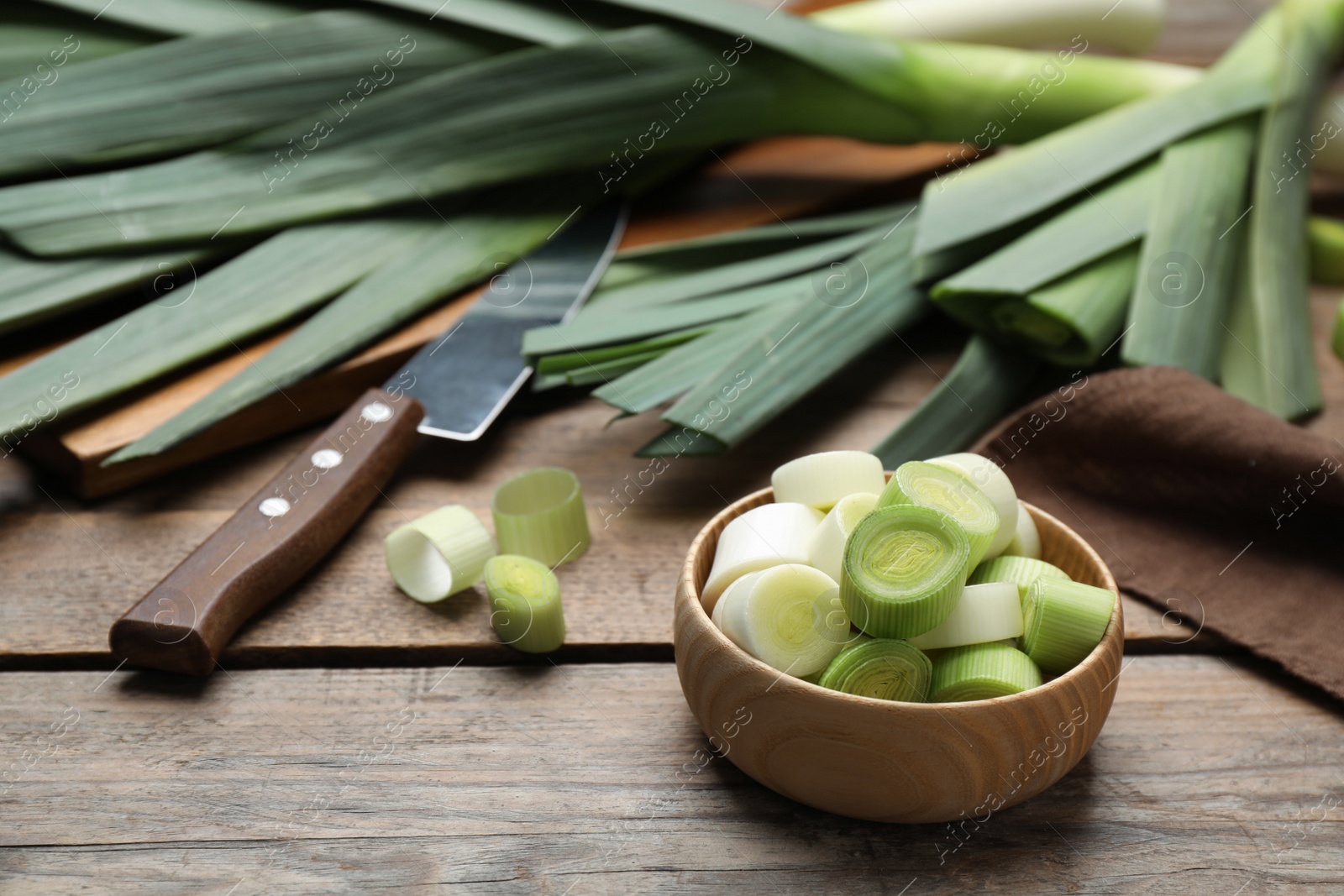 Photo of Cut and whole fresh raw leek on wooden table