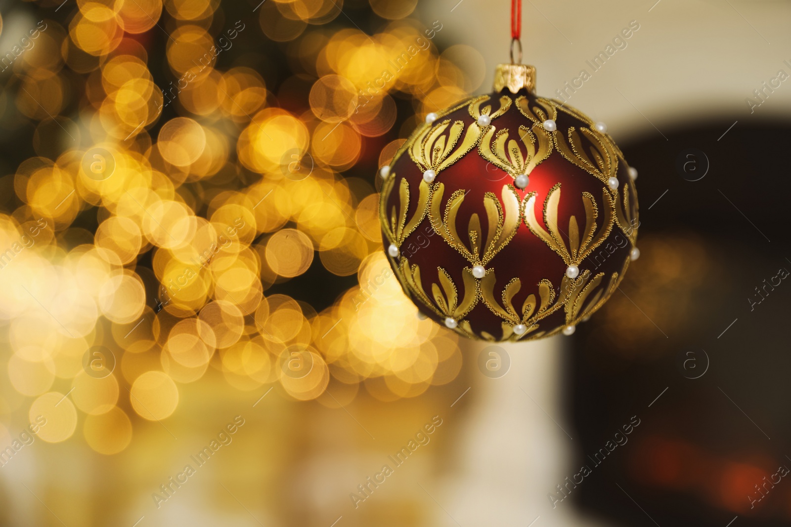 Photo of Beautiful holiday ornament hanging against blurred Christmas lights