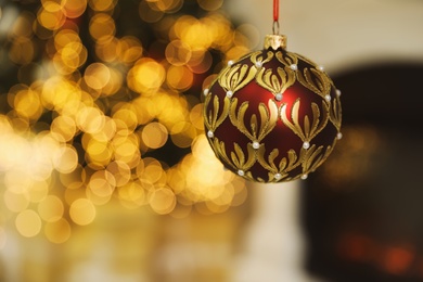 Photo of Beautiful holiday ornament hanging against blurred Christmas lights
