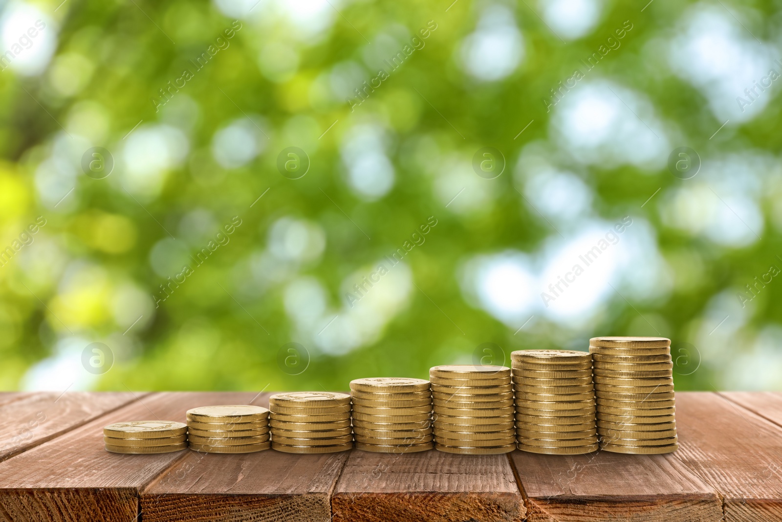 Image of Stacked coins on wooden table against blurred background. Investment concept