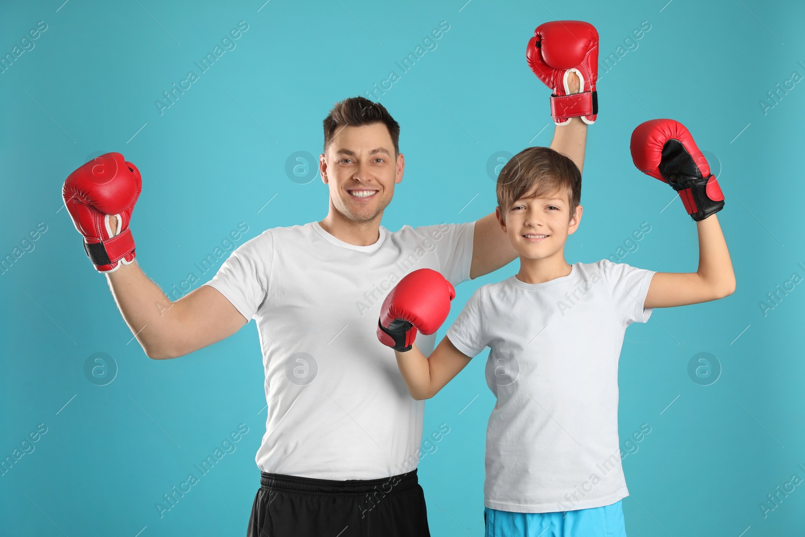 Photo of Emotional dad and his son with boxing gloves on color background