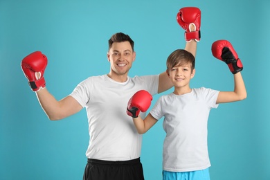 Emotional dad and his son with boxing gloves on color background