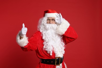 Photo of Merry Christmas. Santa Claus showing thumbs up on red background