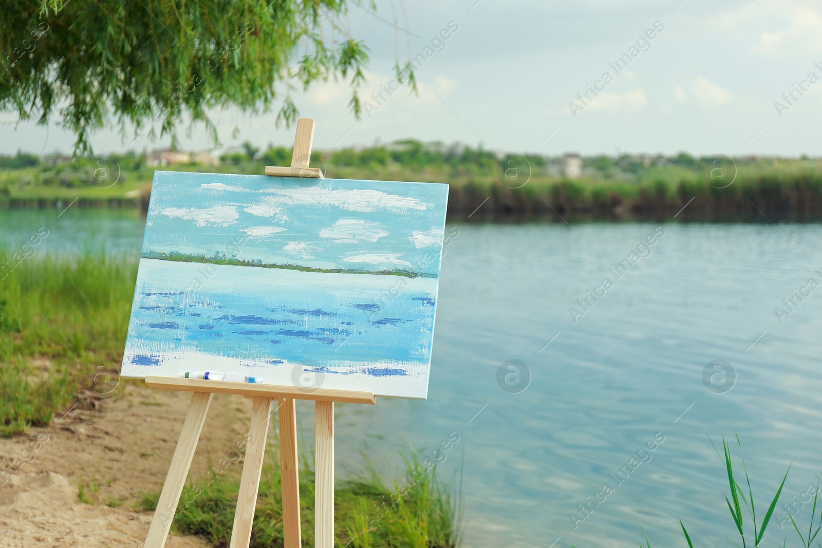 Photo of Wooden easel with unfinished painting near lake