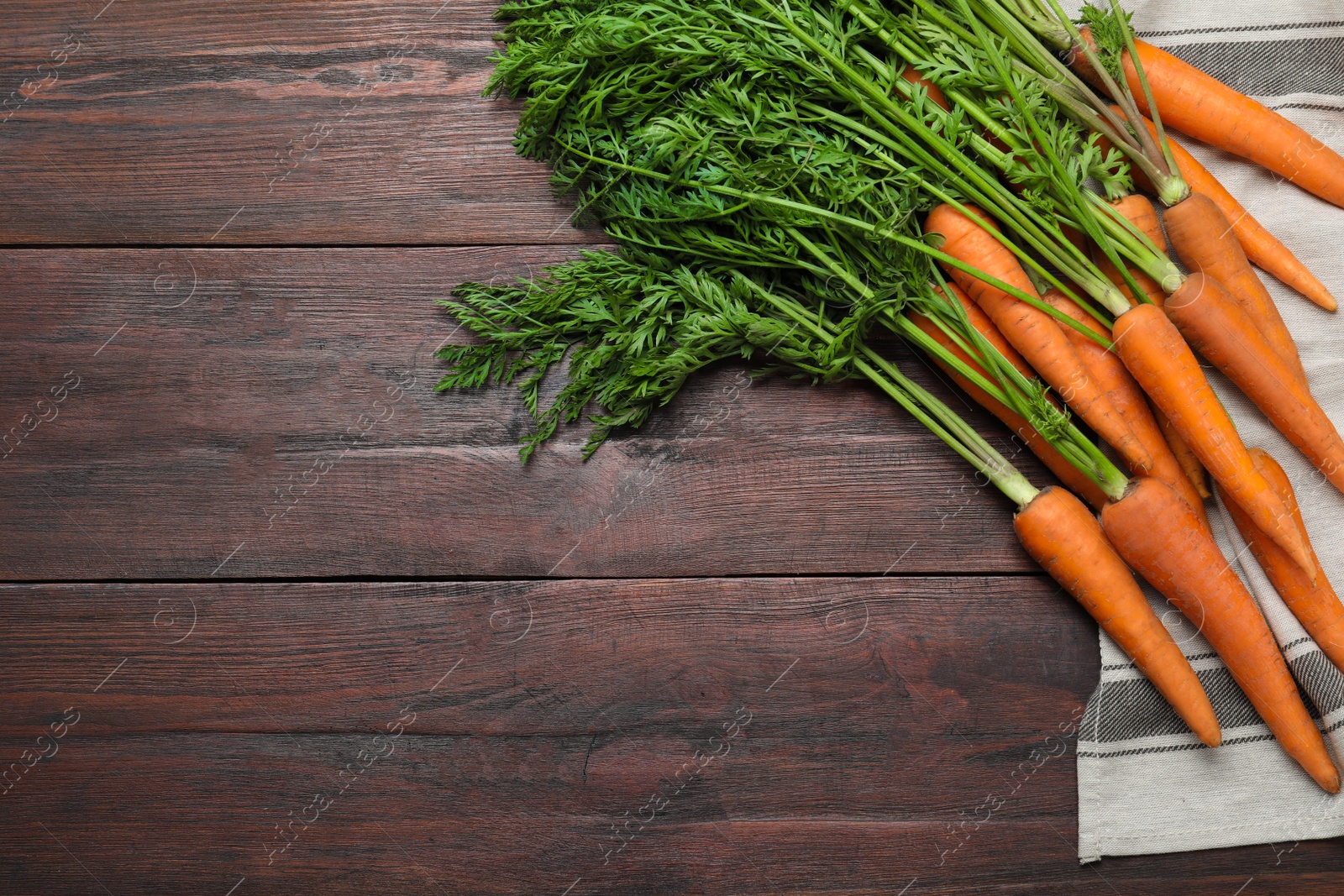 Photo of Ripe carrots on brown wooden table, flat lay. Space for text