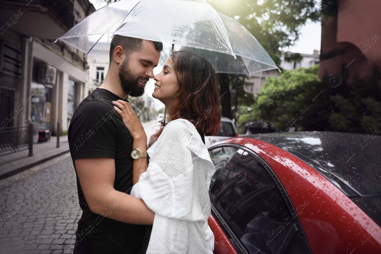 Photo of Young couple with umbrella enjoying time together under rain on city street, space for text