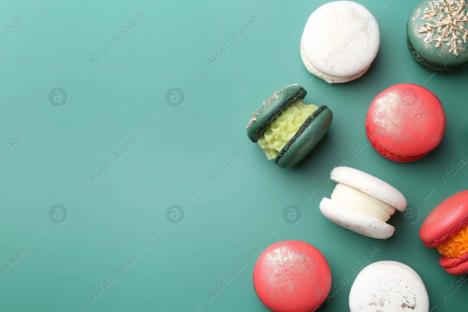 Photo of Beautifully decorated Christmas macarons on green background, flat lay. Space for text