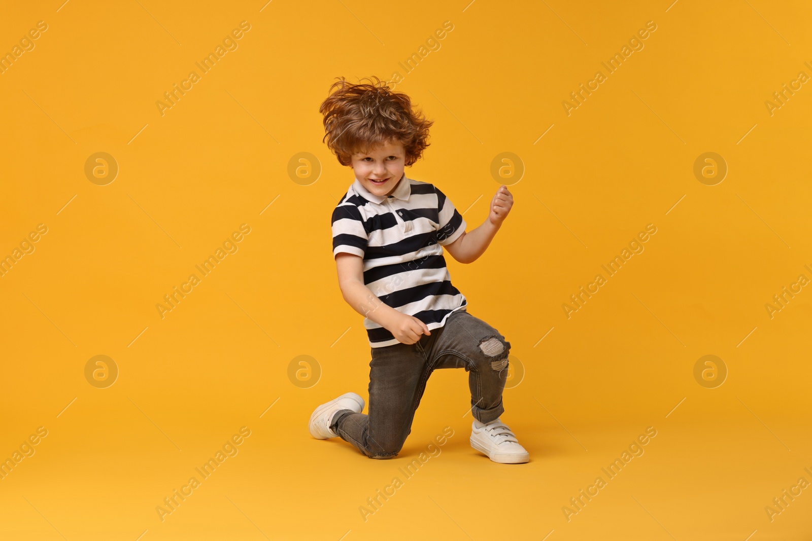 Photo of Happy little boy dancing on yellow background