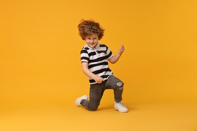 Happy little boy dancing on yellow background