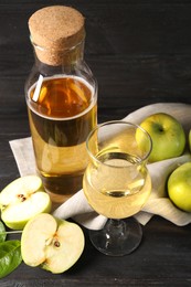 Delicious cider, cut and whole apples on black wooden table, above view