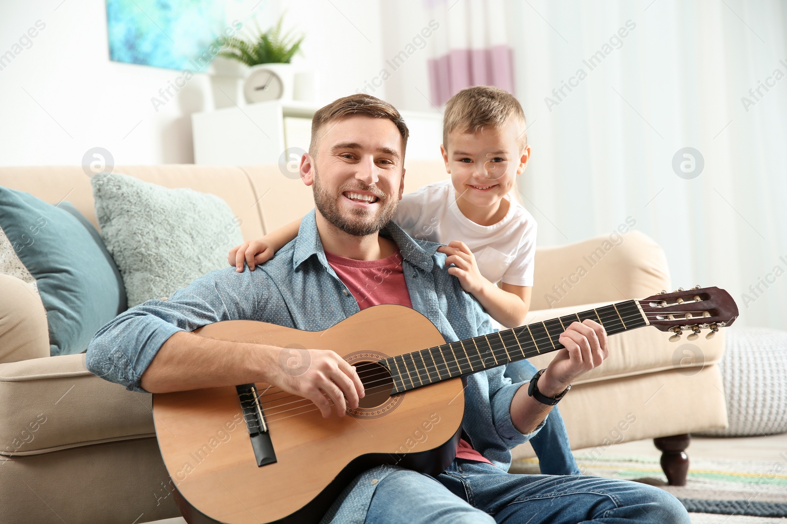 Photo of Father playing guitar for his son at home