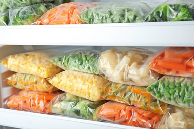 Plastic bags with deep frozen vegetables in refrigerator