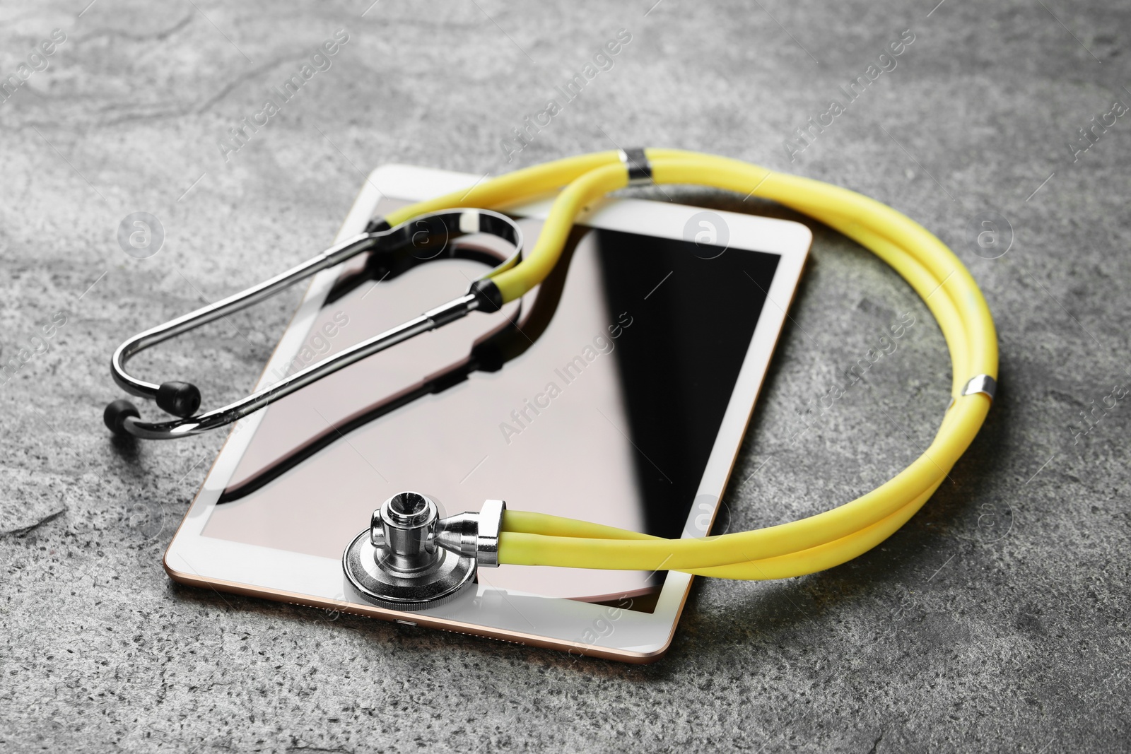 Photo of Modern tablet and stethoscope on grey table