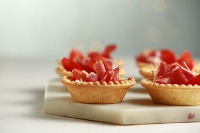 Delicious canapes with jamon on white table, closeup