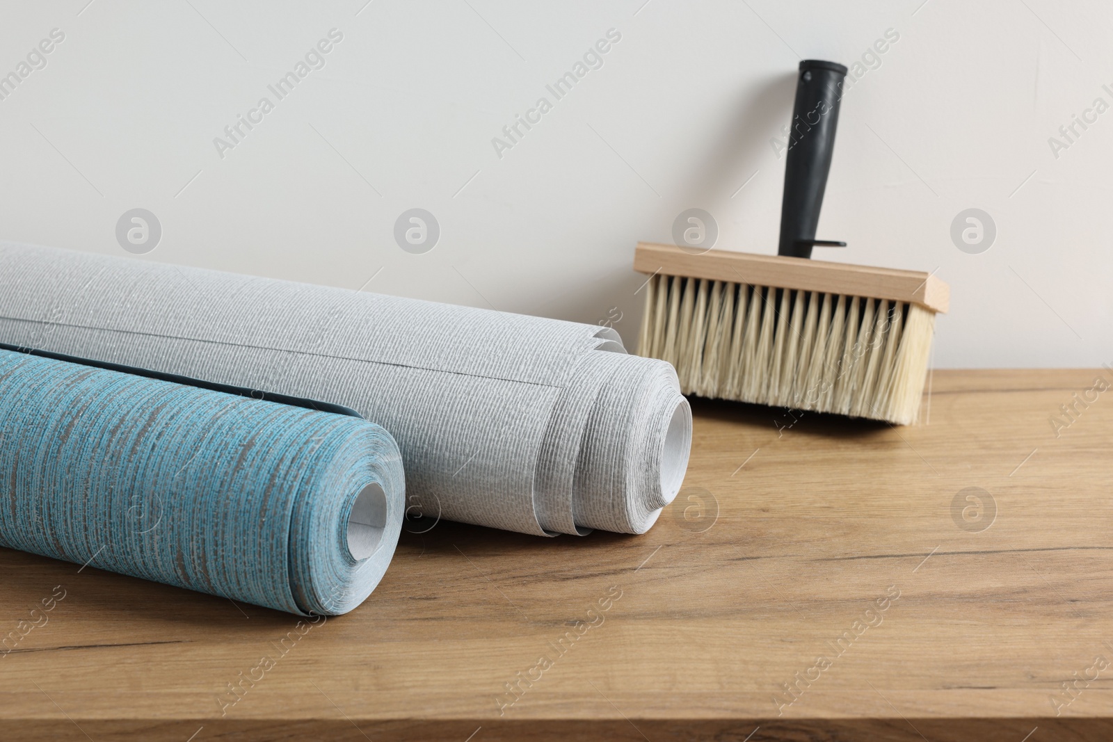 Photo of Wallpaper rolls and brush on wooden table