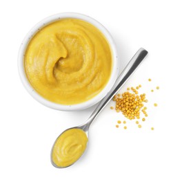 Photo of Fresh tasty mustard sauce in bowl and spoon with dry seeds isolated on white, top view