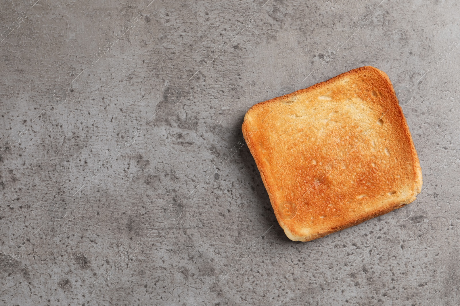 Photo of Slice of delicious toasted bread on gray table, top view. Space for text
