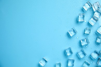 Ice cubes, water drops and space for text on turquoise background, flat lay. Refreshing drink ingredient