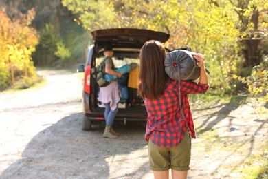 Photo of Female camper with sleeping bag near car outdoors. Space for text