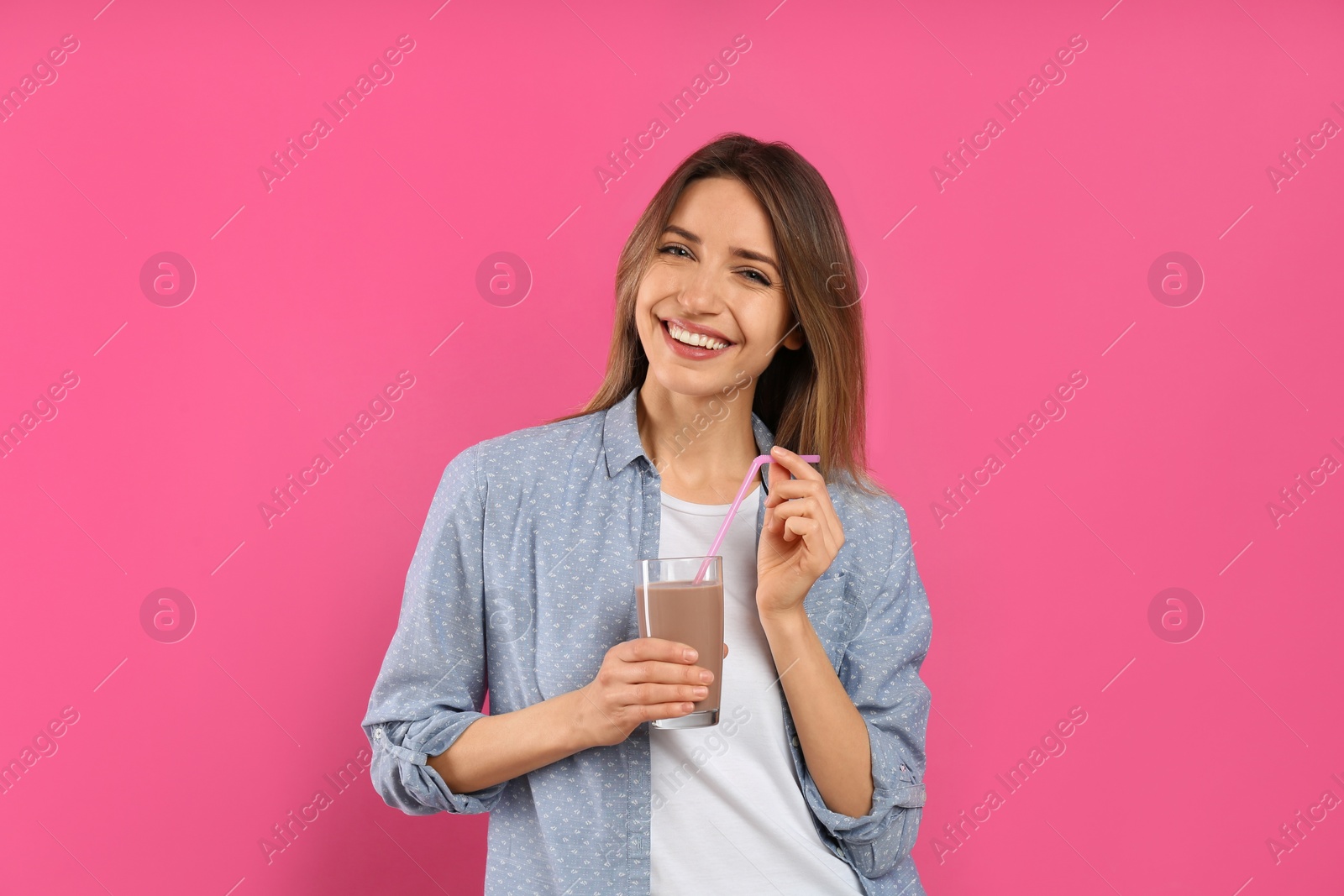 Photo of Young woman with glass of chocolate milk on pink background