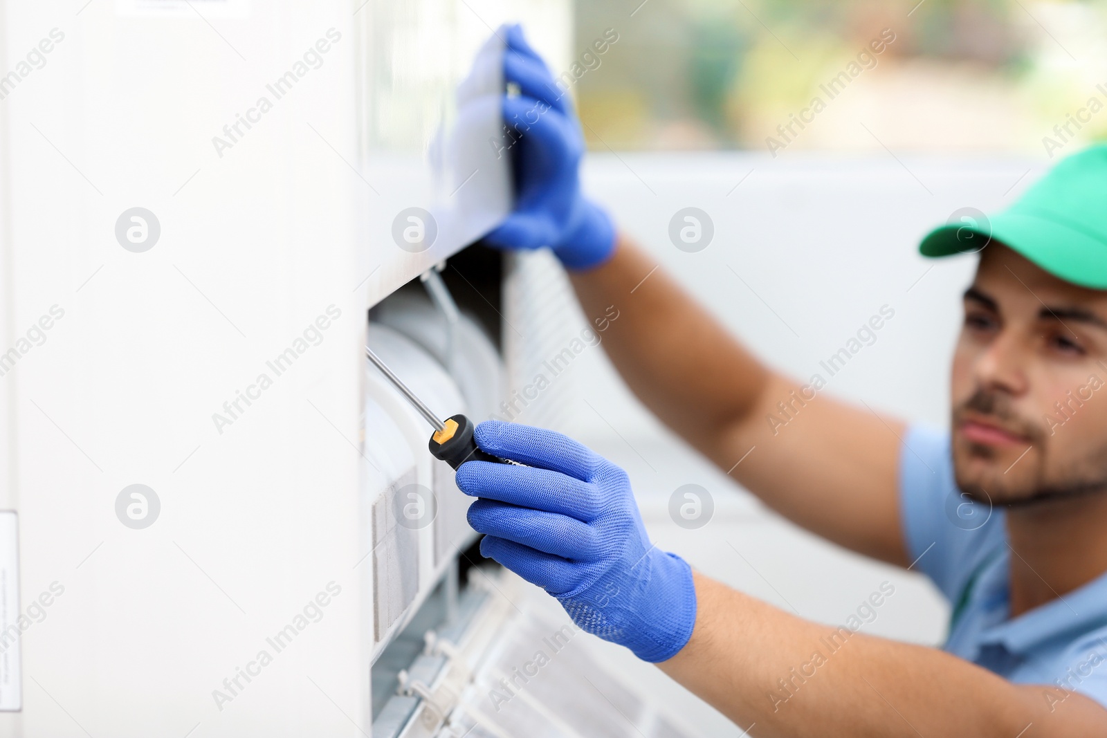 Photo of Professional technician maintaining modern air conditioner indoors, focus on hand