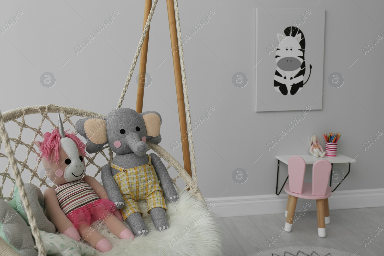 Photo of Stylish child's room interior with adorable painting and hanging chair