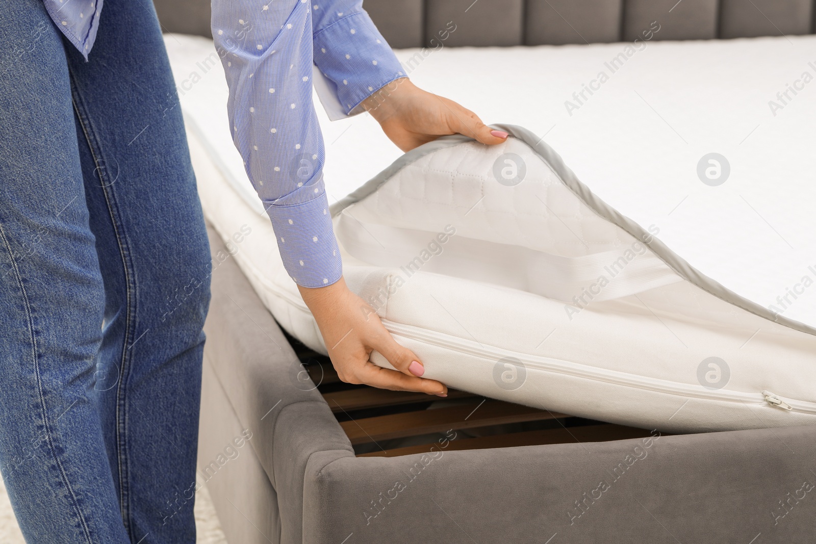 Photo of Woman putting new soft mattress on bed, closeup