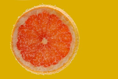 Photo of Slice of grapefruit in sparkling water on yellow background. Citrus soda