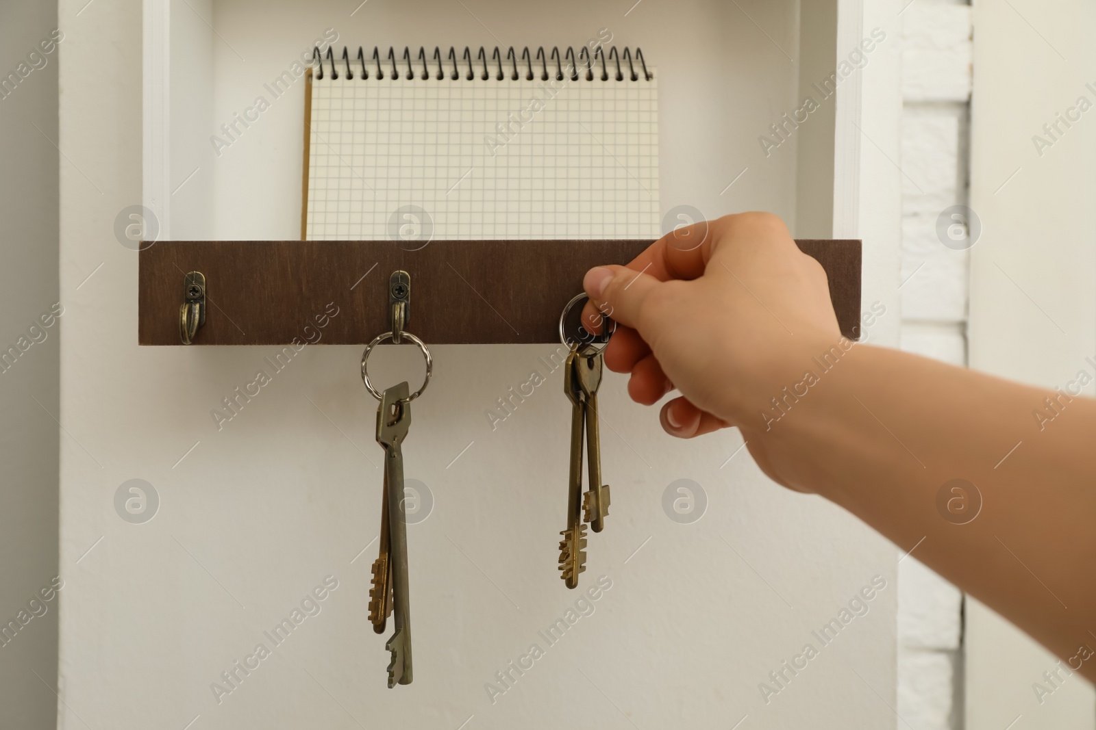 Photo of Woman taking keys from hanger in hallway, closeup