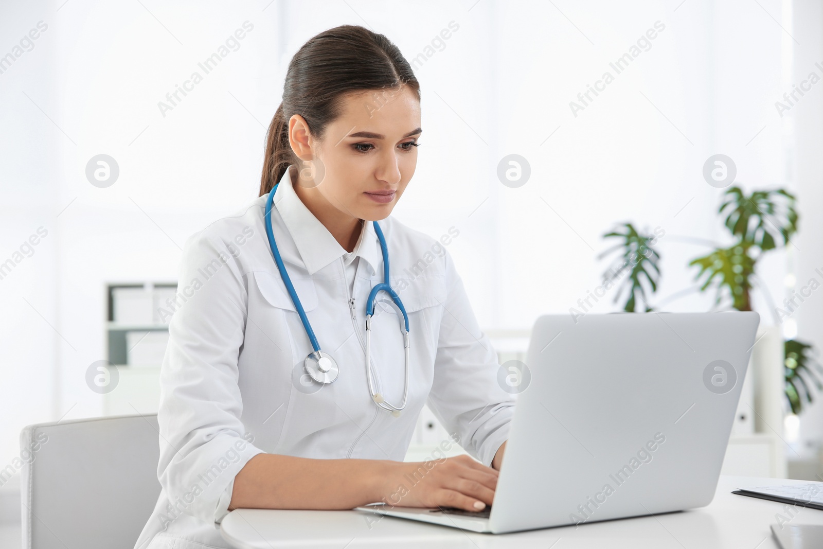 Photo of Female doctor working with laptop at table. Cardiology center