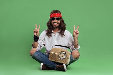 Photo of Stylish hippie man with radio showing V-sign on green background