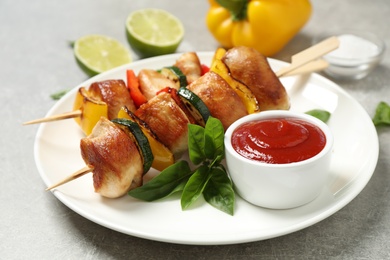 Delicious chicken shish kebabs with vegetables and ketchup on grey table, closeup