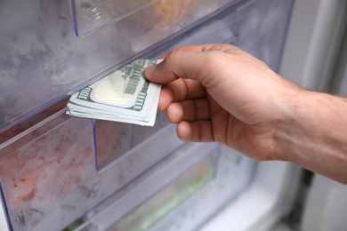 Photo of Man hiding money in refrigerator, closeup. Financial savings