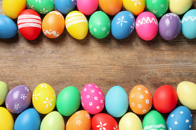 Photo of Frame made with colorful Easter eggs on wooden background. Space for text
